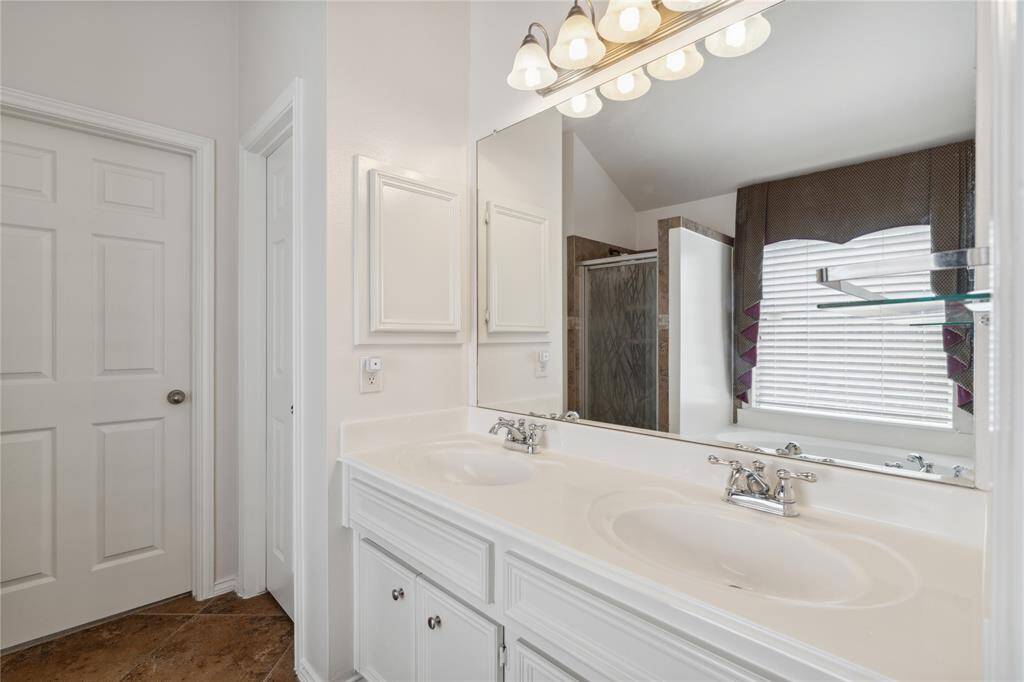 The primary bath features elegant large-format tile flooring, a dual vanity with separate sinks, a relaxing soaking tub, and a sleek glass-framed shower—perfect for starting or ending your day in comfort.