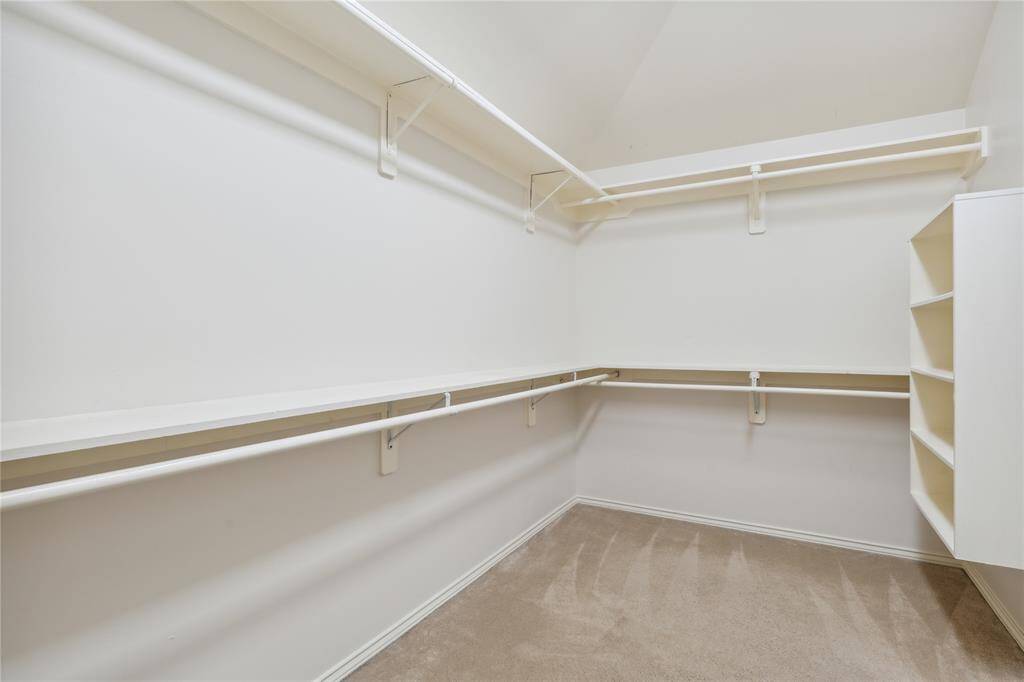 The spacious primary walk-in closet offers ample storage with built-in shelving and hanging space—perfect for keeping your wardrobe organized and easily accessible.