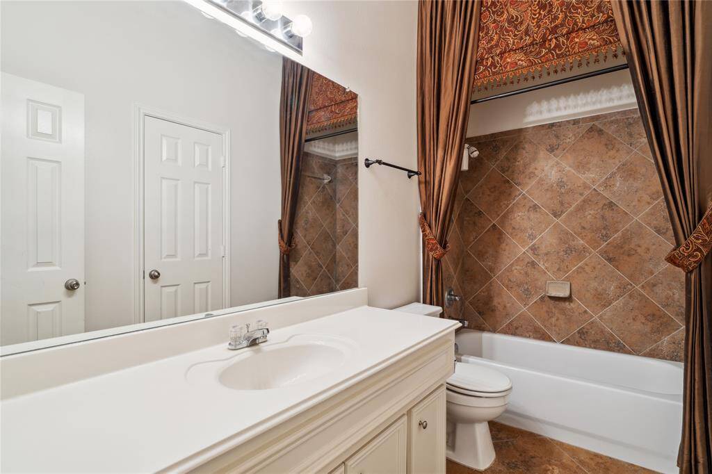 A view of the full secondary bathroom, perfect for guests, featuring stylish custom drapery and a functional, well-maintained layout.