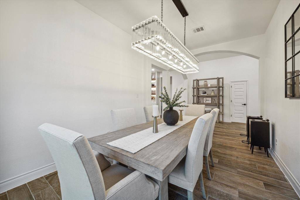The formal dining room embodies architectural elegance and sophistication, featuring high ceilings,tile wood floors, and Restoration Hardware statement light fixtures that create an ambiance of style and warmth.