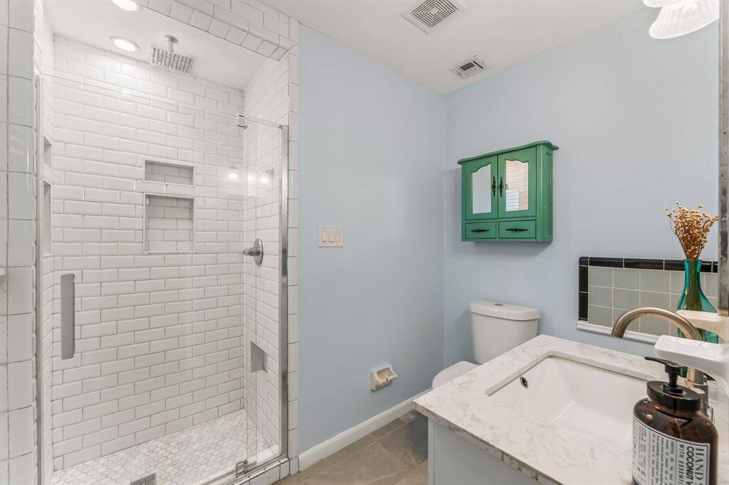 Upgraded primary bathroom with full ceramic tile walls, oversized showerhead and elongated commode