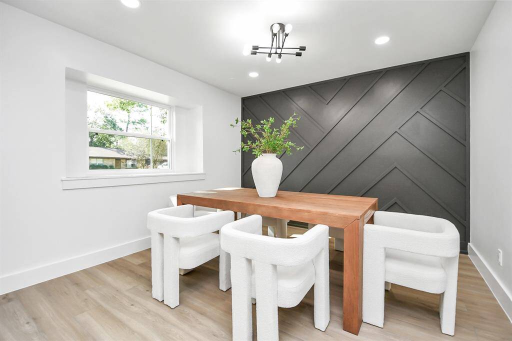 Modern dining area with herringbone accent wall, large window, contemporary lighting fixture.