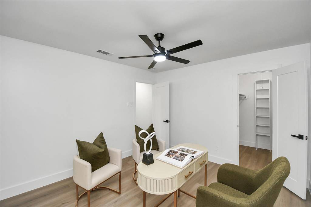 You’re viewing a modern, well-lit room with a stylish ceiling fan, neutral walls, and waterproof rigid core luxury vinyl flooring. This versatile space includes a walk-in closet, making it ideal as a home office, reading nook, or guest room.