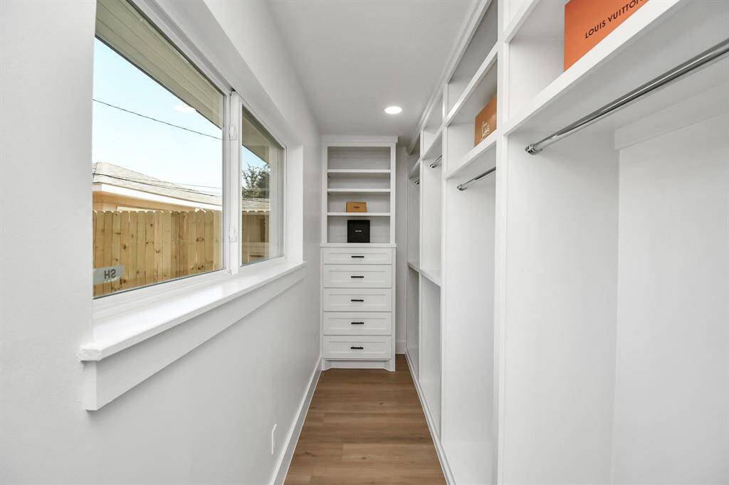 This is a spacious, well-lit walk-in closet with ample built-in shelving, featuring a clean and modern design with The light waterproof rigid core luxury vinyl flooring . Perfect for organizing clothing and accessories.
