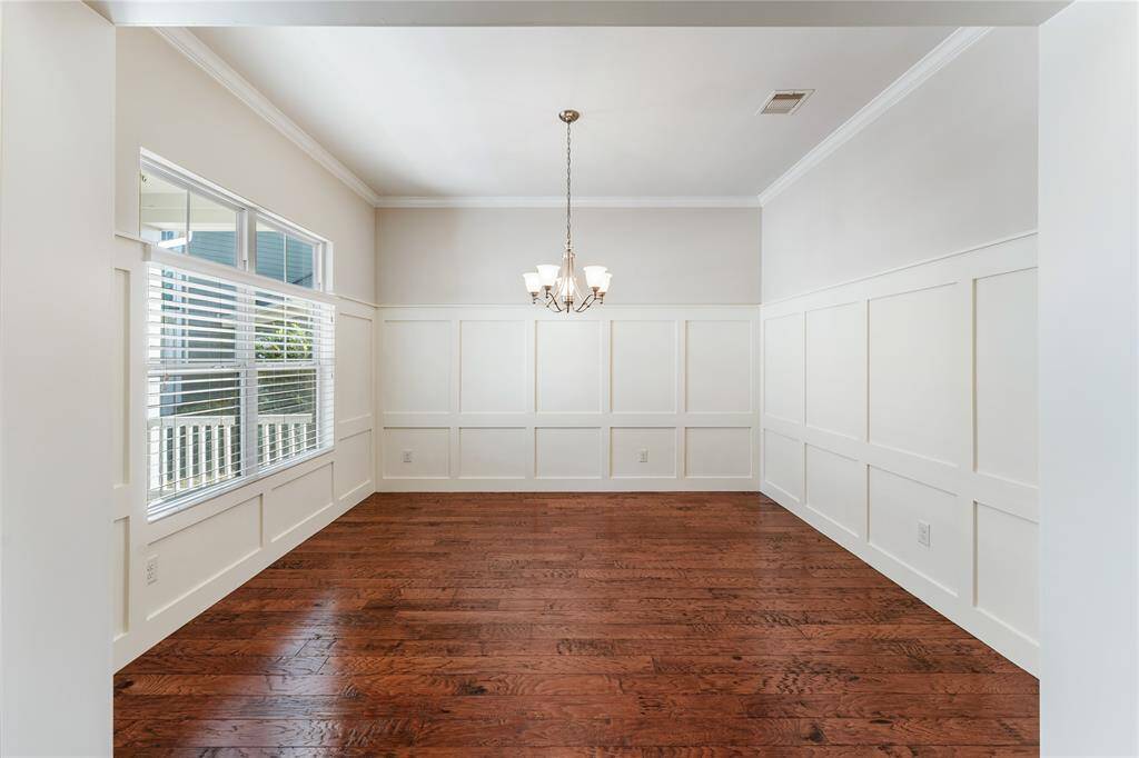 Elegant board and battten wall details and High-ceilings and hardwood floors create a formal feeling, yet the windows soften the appearance for a formal dining area.