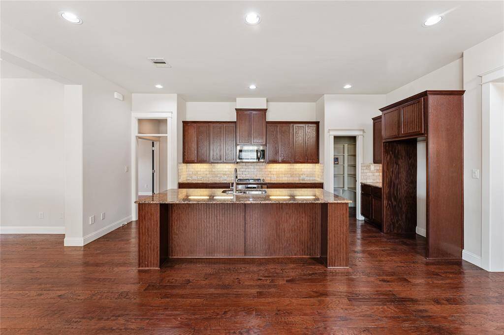 Open concept living! Ample cabinetry and gleaming granite countertops complement one another in texture and color, while the stainless-steel appliances add balance and sheen.