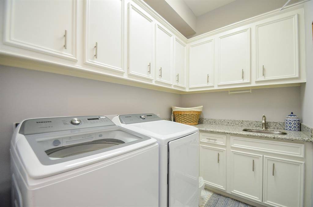Good size laundry room with tons of cabinets and sink with granite countertop.