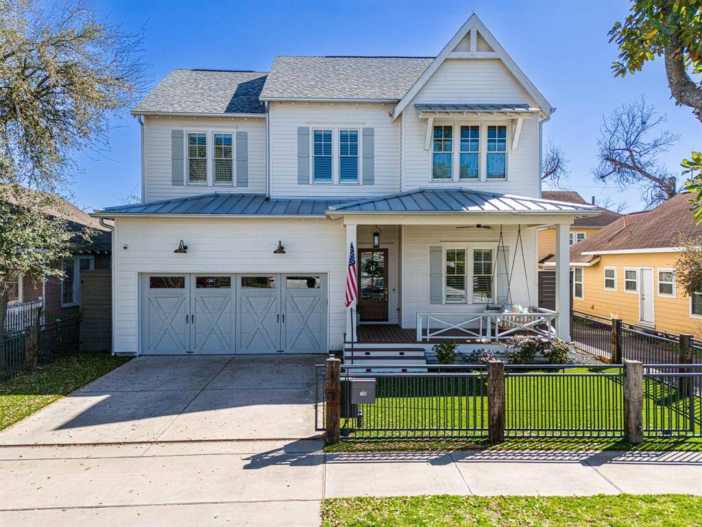 Charming two-story home with a modern farmhouse style, featuring a spacious front porch with a swing, a neatly landscaped yard, and a double garage. The exterior is accented with white siding and partial metal roof, providing a clean and inviting look.