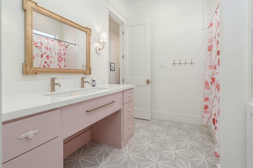 Double vanity with a pink cabinet, modern fixtures, and a large mirror.