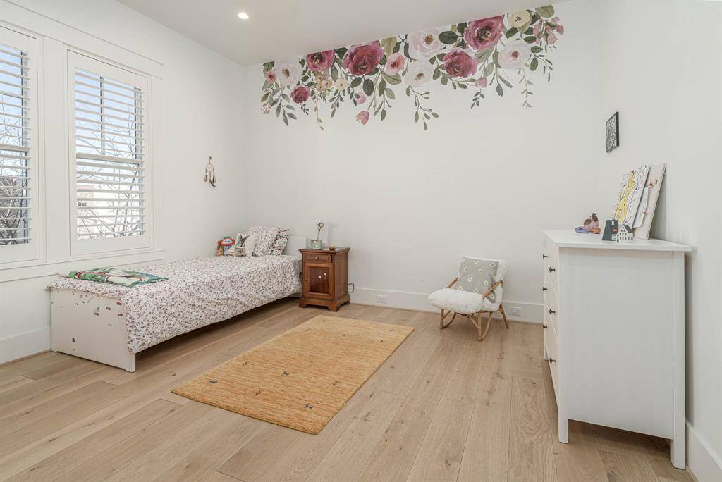 bedroom #4 features a large window with shutters, removable floral wall accents, and light wood flooring.