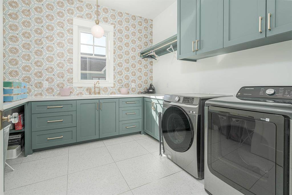 Upstairs laundry room featuring teal cabinetry, and a patterned tile backsplash. It includes ample counter space, and storage.