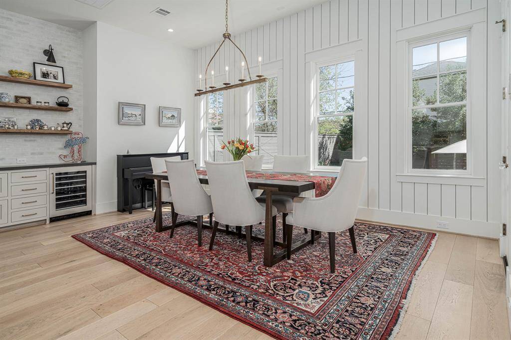 This dining area features a bright, airy design with large windows and white shiplap walls.