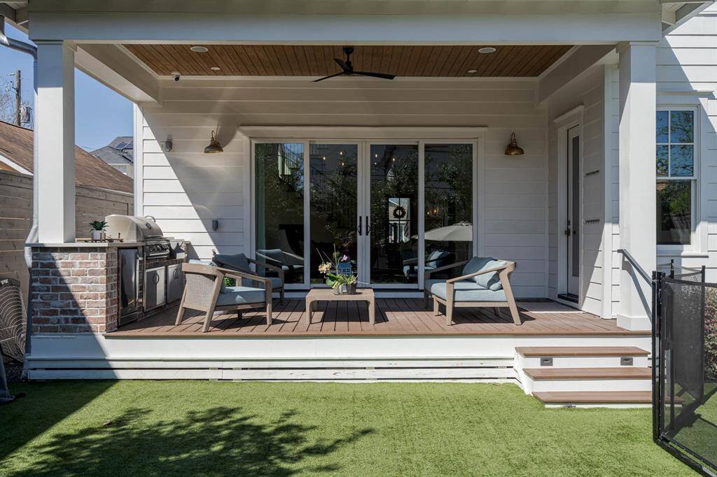 Inviting patio with a covered deck with comfortable seating, a built-in grill, and ceiling fan.