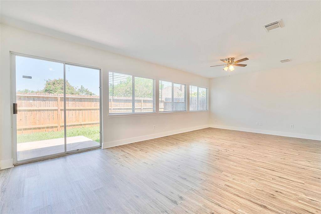 A view of the living room with plenty of natural light shining through the sliding doors and wall of windows