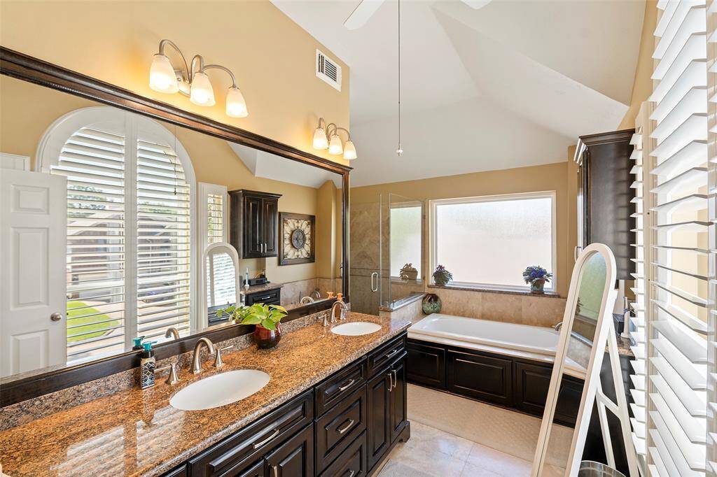 Gorgeous primary bathroom with dual sinks, granite countertops, separate soaking tub, and walk-in shower.