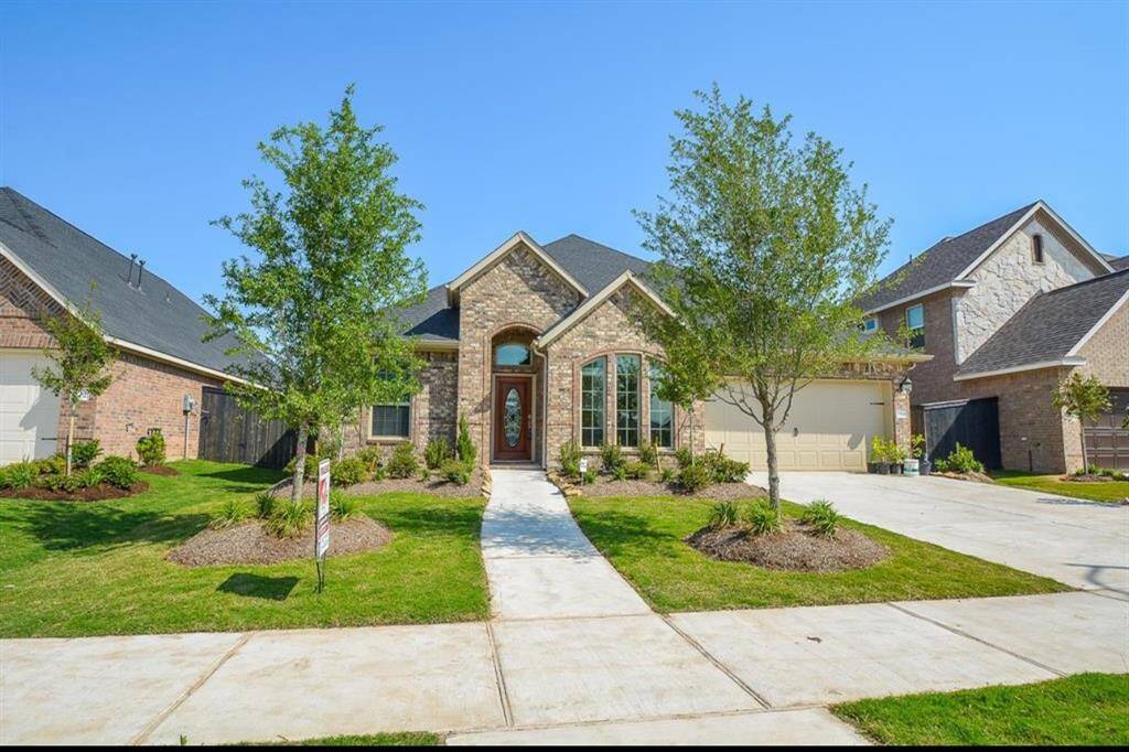 This is a charming single-story brick home with a well-maintained front yard featuring trees and shrubs. It has a welcoming entrance, large windows, and a car garage. The driveway and pathways are paved, enhancing curb appeal.