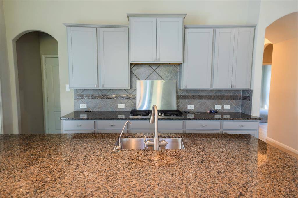 Modern kitchen with granite countertops, stainless steel appliances, and ample cabinet space. The open layout is enhanced by a central island with a built-in sink.