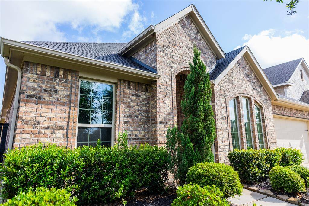 Charming brick home with a well-maintained exterior, featuring large windows and lush landscaping. Perfect for those seeking curb appeal and natural light.