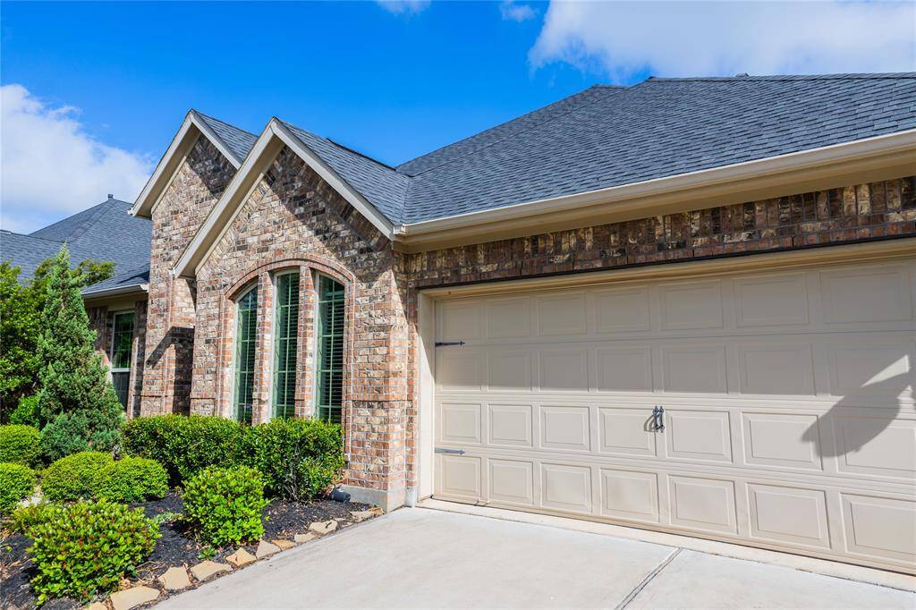 This photo showcases a charming home with a brick exterior and car garage. It features a well-maintained front yard with neatly trimmed bushes and a concrete driveway, offering great curb appeal.