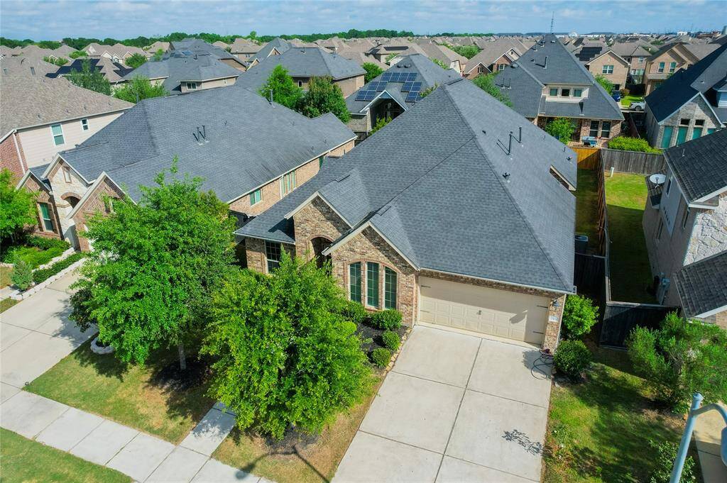 This photo showcases a spacious, modern suburban home with a well-maintained front yard, a two-car garage, and a brick exterior. It's located in a neighborhood with similar styled homes, offering a cohesive and pleasant community feel.