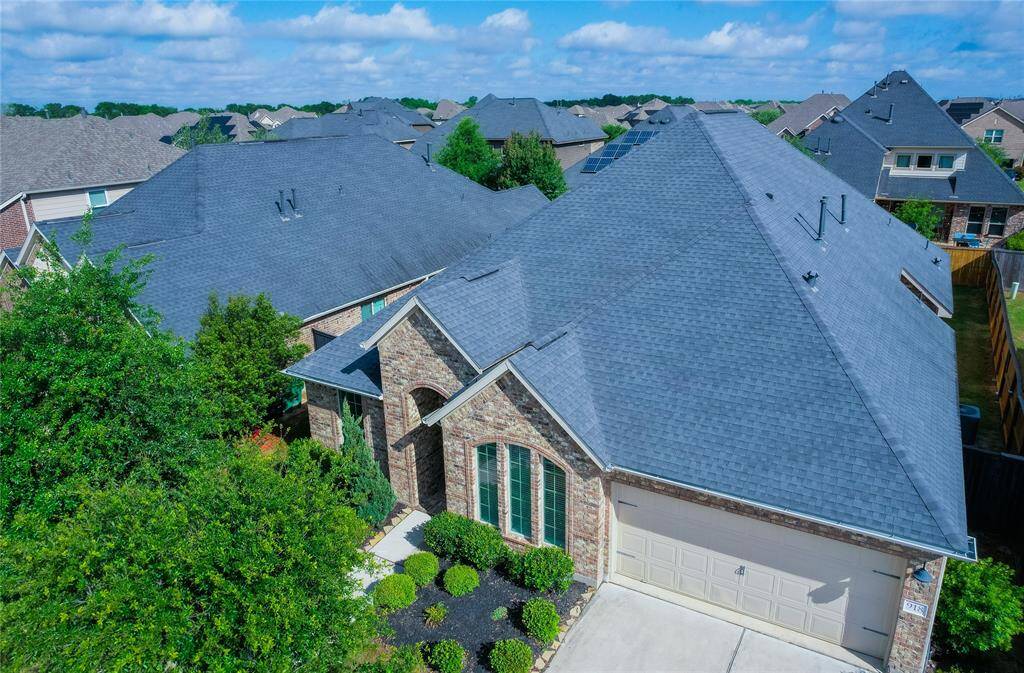 This photo showcases a charming brick home with a well-maintained roof and neat landscaping. It features a two-car garage and is situated in a neighborhood with similar style houses, offering a suburban feel.
