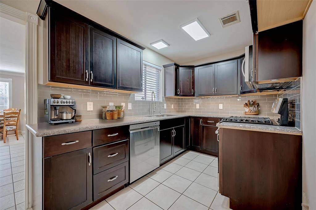 The fully renovated kitchen features warm, rich cabinetry, granite countertops, and stainless appliances. Stainless steel refrigerator, not shown, IS included.