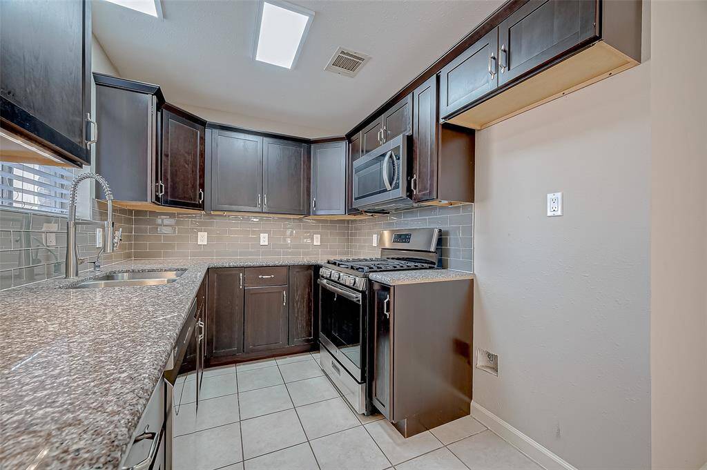 The fully renovated kitchen features warm, rich cabinetry, granite countertops, and stainless appliances. Stainless steel refrigerator, not shown, IS included.