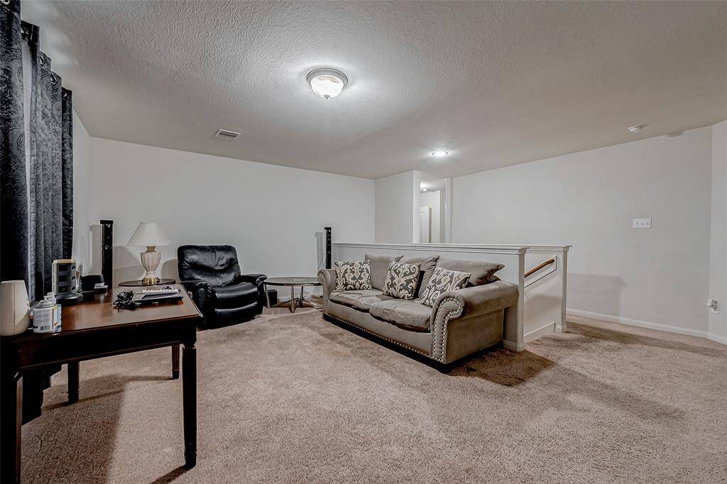 The upstairs landing offers a generous open area, perfect for a game room or lounge. Plush carpeting and large windows enhance the comfort of the space.