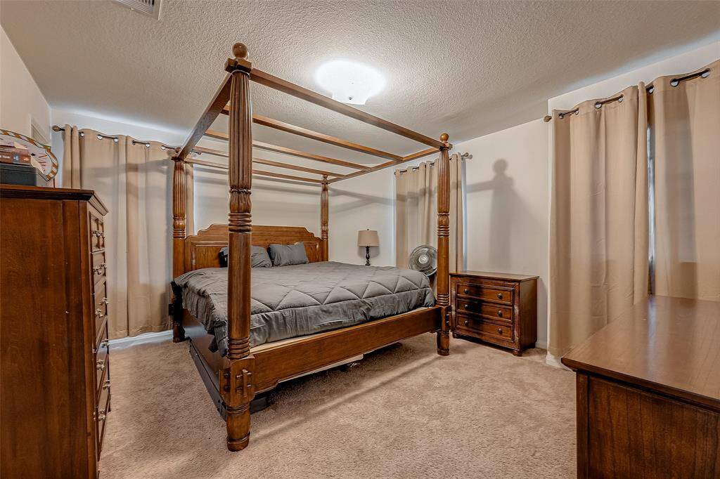A bright and spacious bedroom with large windows and soft carpeting, ready to accommodate a variety of furniture arrangements.