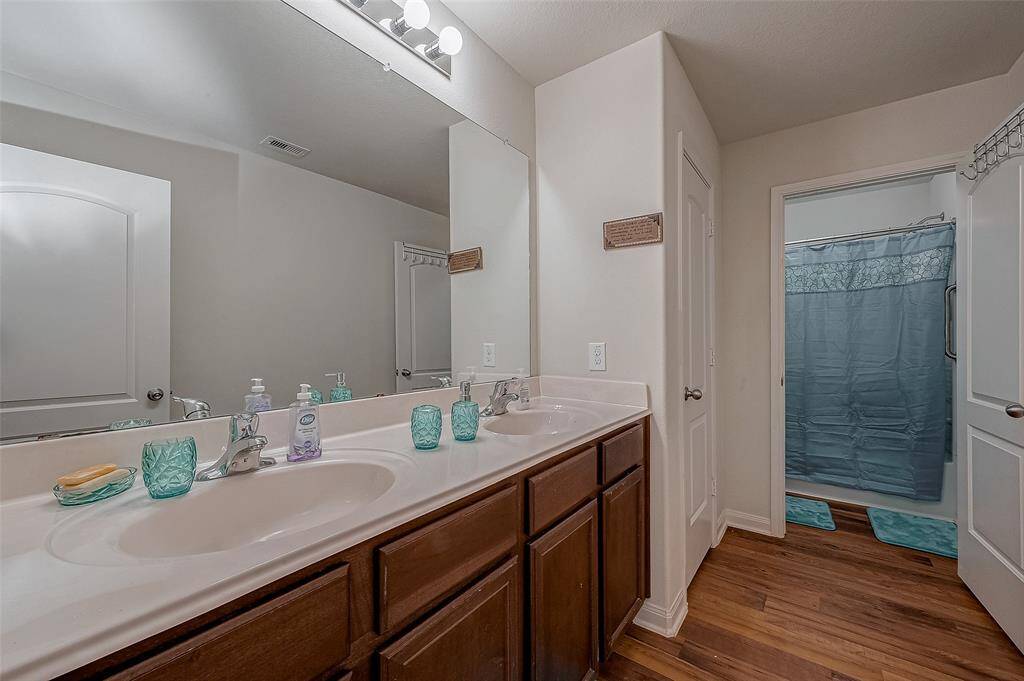 The secondary bathroom is designed for shared use, with a dual-sink vanity and a separate vanity area for added functionality.
