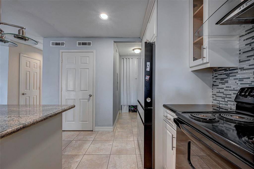 The granite countertop island offers additional workspace, while the neutral tile flooring complements the light walls for a bright, open feel.