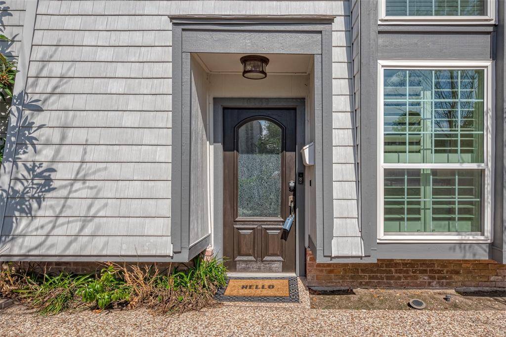 The exterior features light gray siding with a modern design and large windows with shutters, creating a warm and inviting curb appeal.