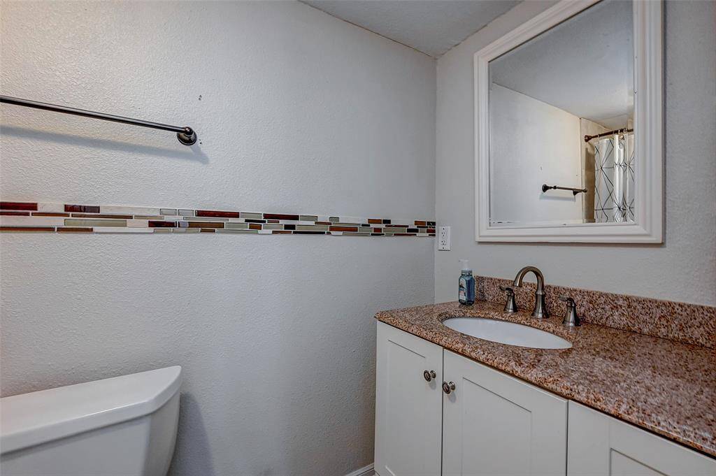 This bathroom features a modern vanity with a granite countertop, a sleek undercount sink, and a framed mirror.