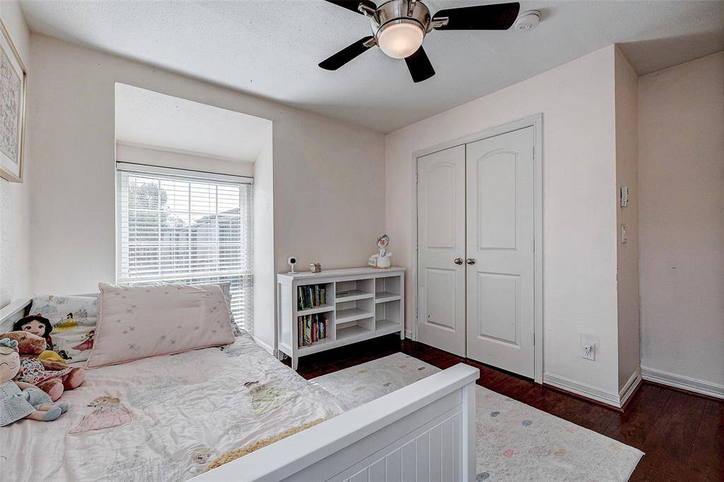 The room has a ceiling fan and a double-door closet, with light walls and dark wood flooring. Ideal for a child's room.