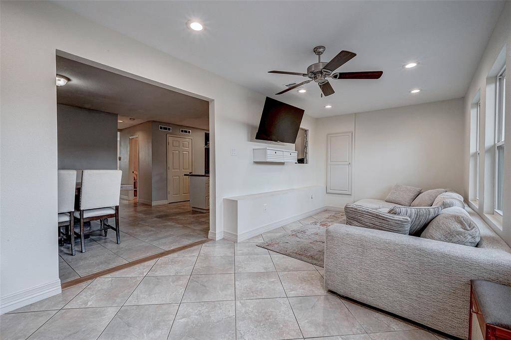 This inviting living space features a cozy tile flooring, and ample natural light from large windows. The room opens into a dining area, providing a seamless flow for entertaining.