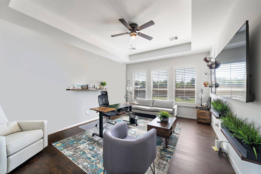 Primary bedroom is downstairs and spacious and features trey ceilings, hardwood flooring and plantation shutters.
