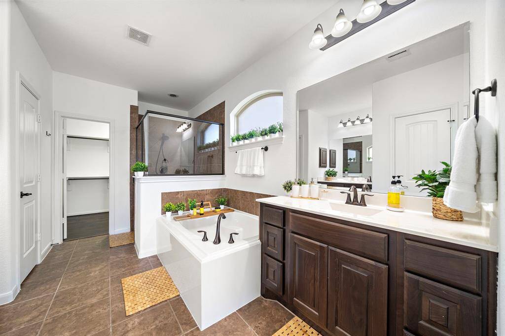 Dual vanities, garden tub, separate shower and a large walk-in closet standout in the primary bath of this custom home.
