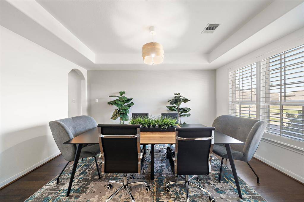 Formal dining features trey ceilings and hardwood floors.