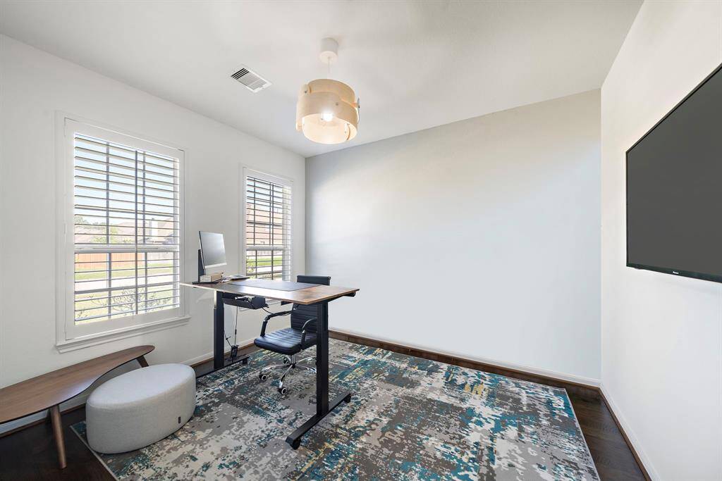 Home office/study with plantation shutters and hardwood floors.