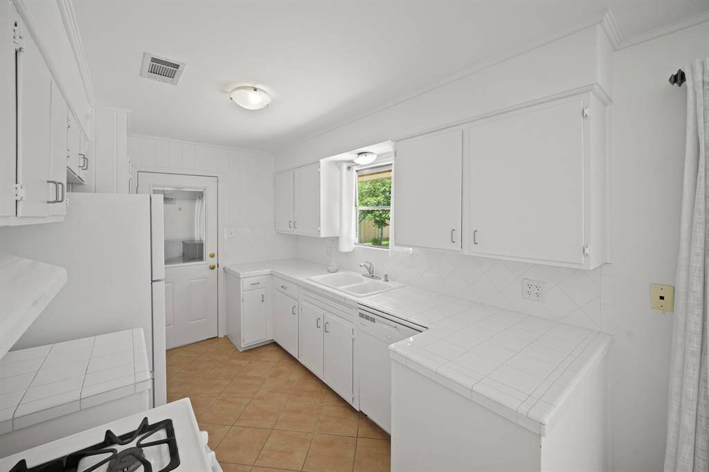 The Kitchen offers a Kohler White Porcelain Sink (2 Basins), Polished Chrome Kitchen Faucet, Polished Chrome Soap Dispenser, and 2 Tiered Double Door Pantry.  A Picture Sized Window (with White Linen Style Fabric Tab Curtains) is located above the Kitchen Sink and views the Park-Like Backyard.