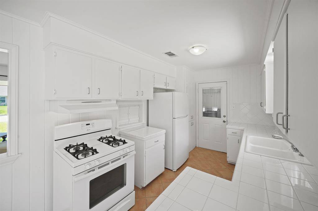 Enjoy preparing Meals on the White Amana 4 Burner Gas Range, with Oven below.  Additional Amenities in the Kitchen include a White Frigidaire Refrigerator (Remains per Seller), White Range Hood, Fresh White Designer Paint, and Diagonally Set Light Terra Cotta Hued Tile Floors.