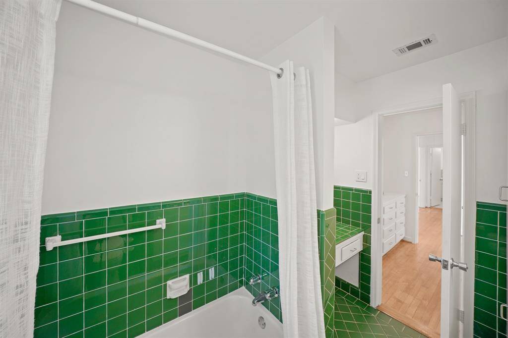 A Full Tub with Retro Emerald Green Tile Surround, Polished Chrome Faucet, and Polished Chrome Handles is featured in the Primary Bath.