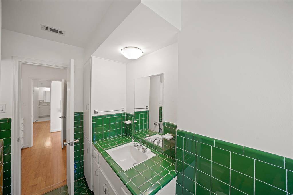 Additional Features in the Primary Bath include a Built in Linen Cabinet, Built in Storage Cabinet, and Retro Emerald Green Tile Floors.