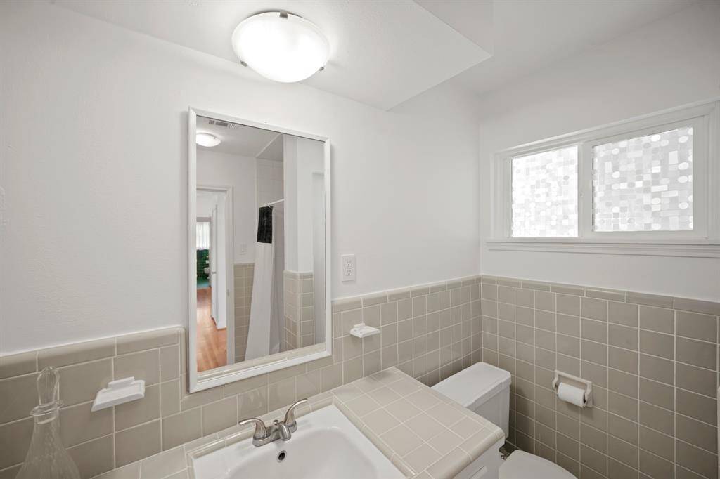 Additional Features in the Hall/Guest Bath include a Retro Grey Green Tile Topped Vanity, Undermount  Porcelain Sink, Polished Nickel Faucet, Framed Mirror above the Sink,Fresh White Designer Paint, and a Flush Mount Light Fixture.