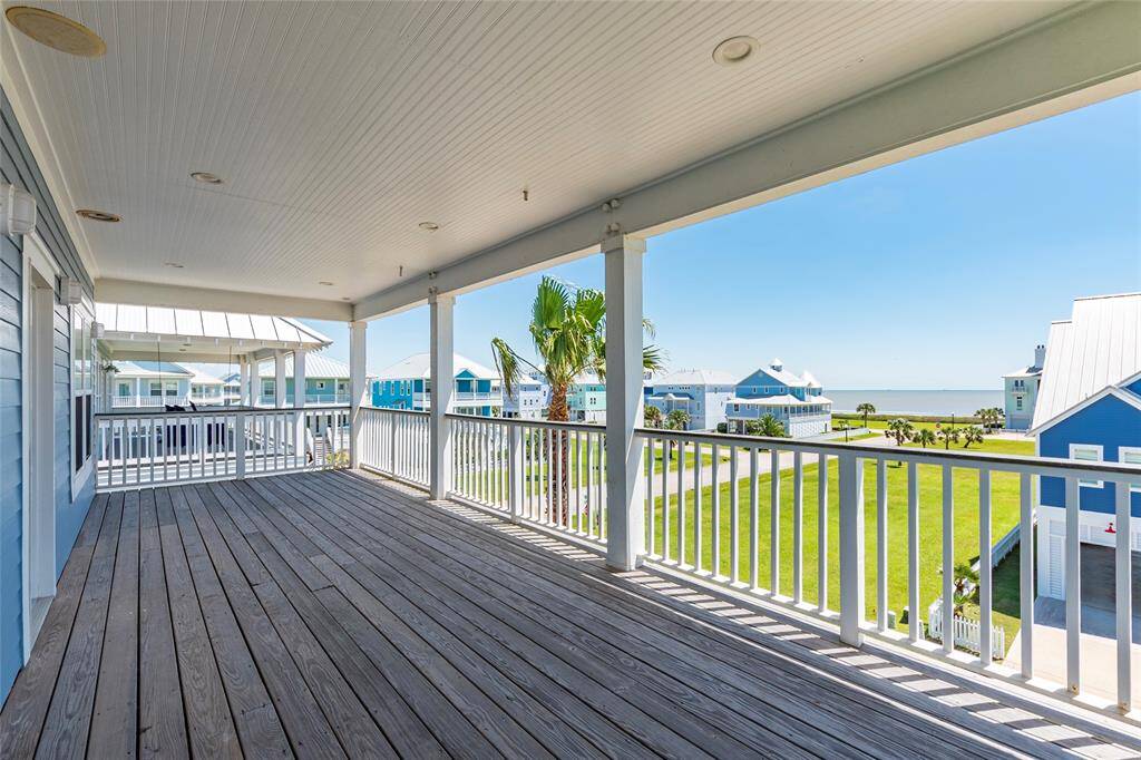 Spacious covered deck with wooden flooring offers scenic views of a coastal neighborhood and the ocean. Ideal for relaxing or entertaining.
