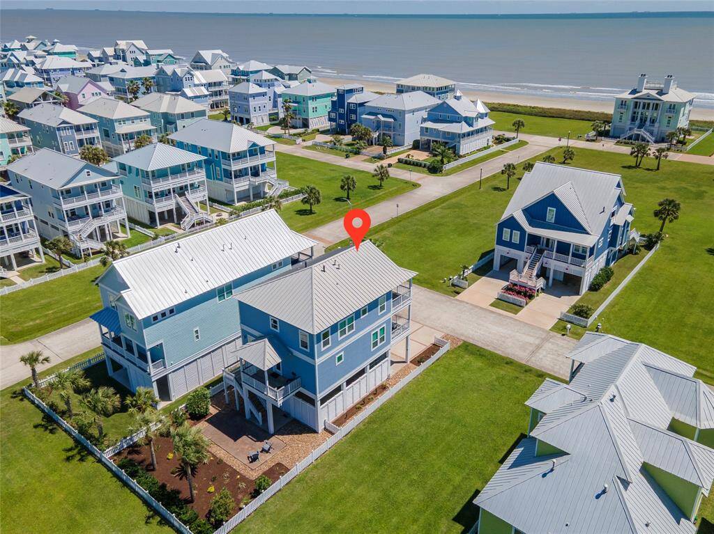 This coastal property features a charming, multi-story home with a metal roof, set in a picturesque neighborhood near the beach. It boasts a spacious yard with landscaped garden areas, and offers easy access to the shoreline, perfect for seaside living.