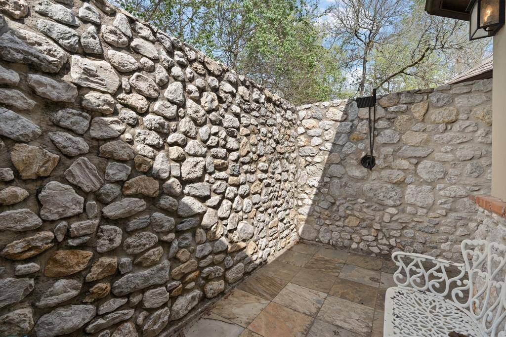 Step into the natural oasis of the outdoor shower, nestled within a serene enclave surrounded by a rustic rock wall, where the harmony of nature meets the indulgence of relaxation.