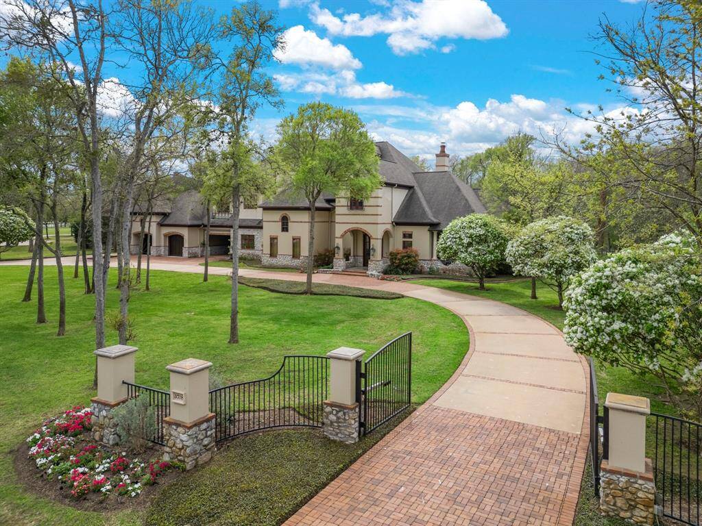 Nestled behind a lush row of trees, the home reveals itself with a stunning driveway that meanders gracefully through meticulously landscaped gardens.