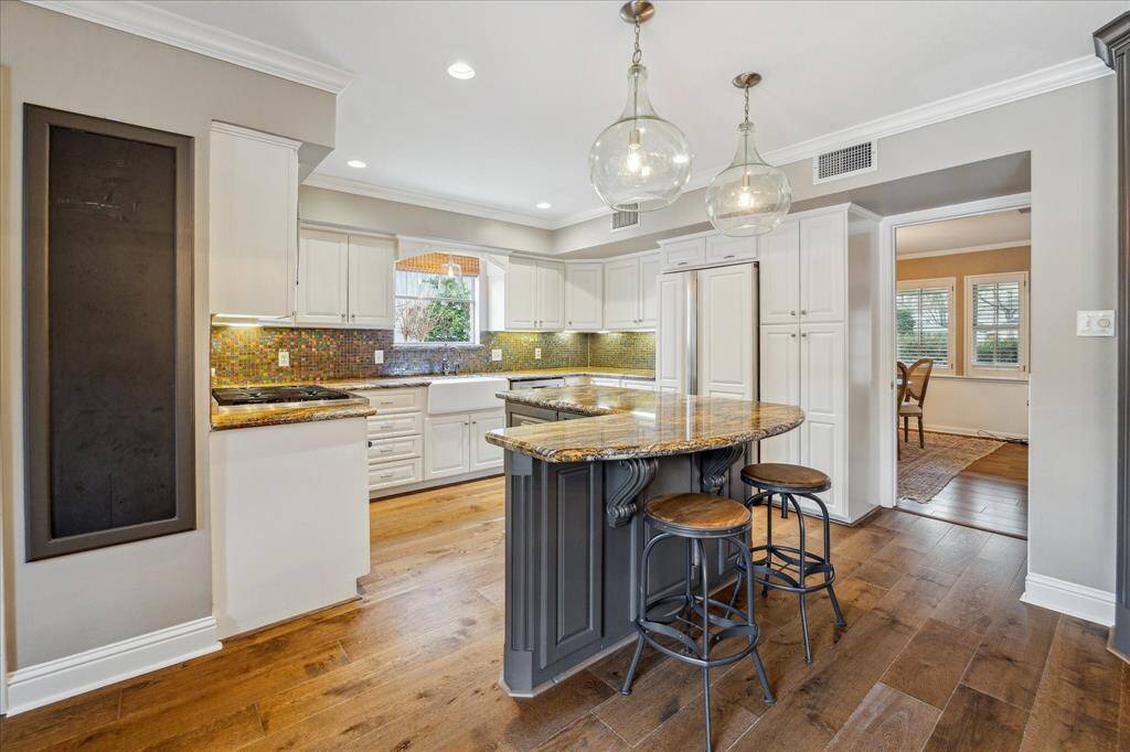 Another view of the kitchen with paneled refrigerator and farm sink