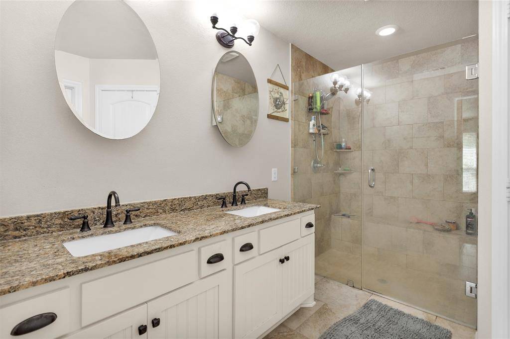 Primary bath offers double sinks, tile flooring and large walk in shower.